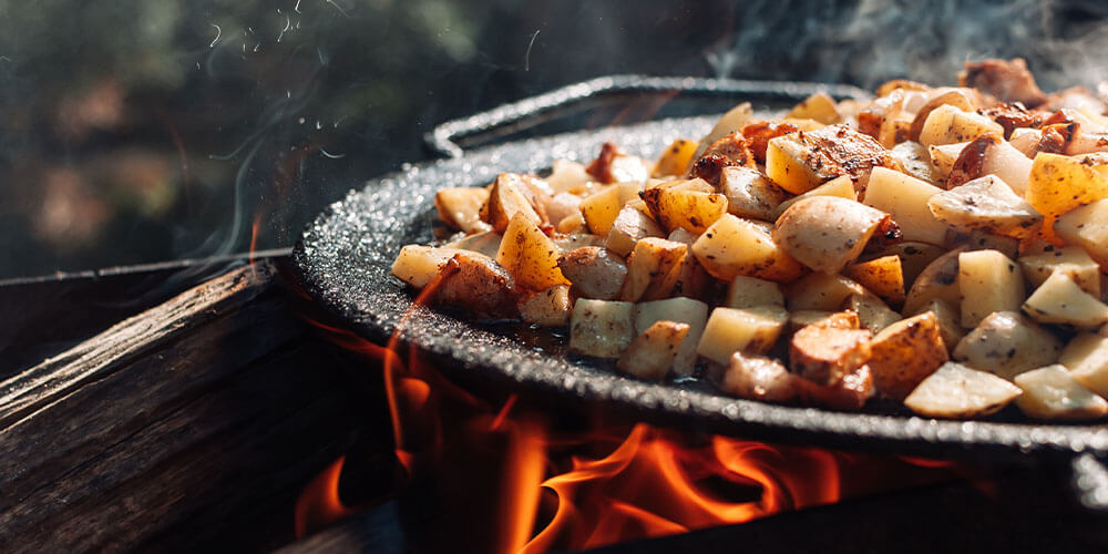 Eising Garden Centre - Tips for Designing the Perfect Summer Fire Pit- -roasting potatoes over fire